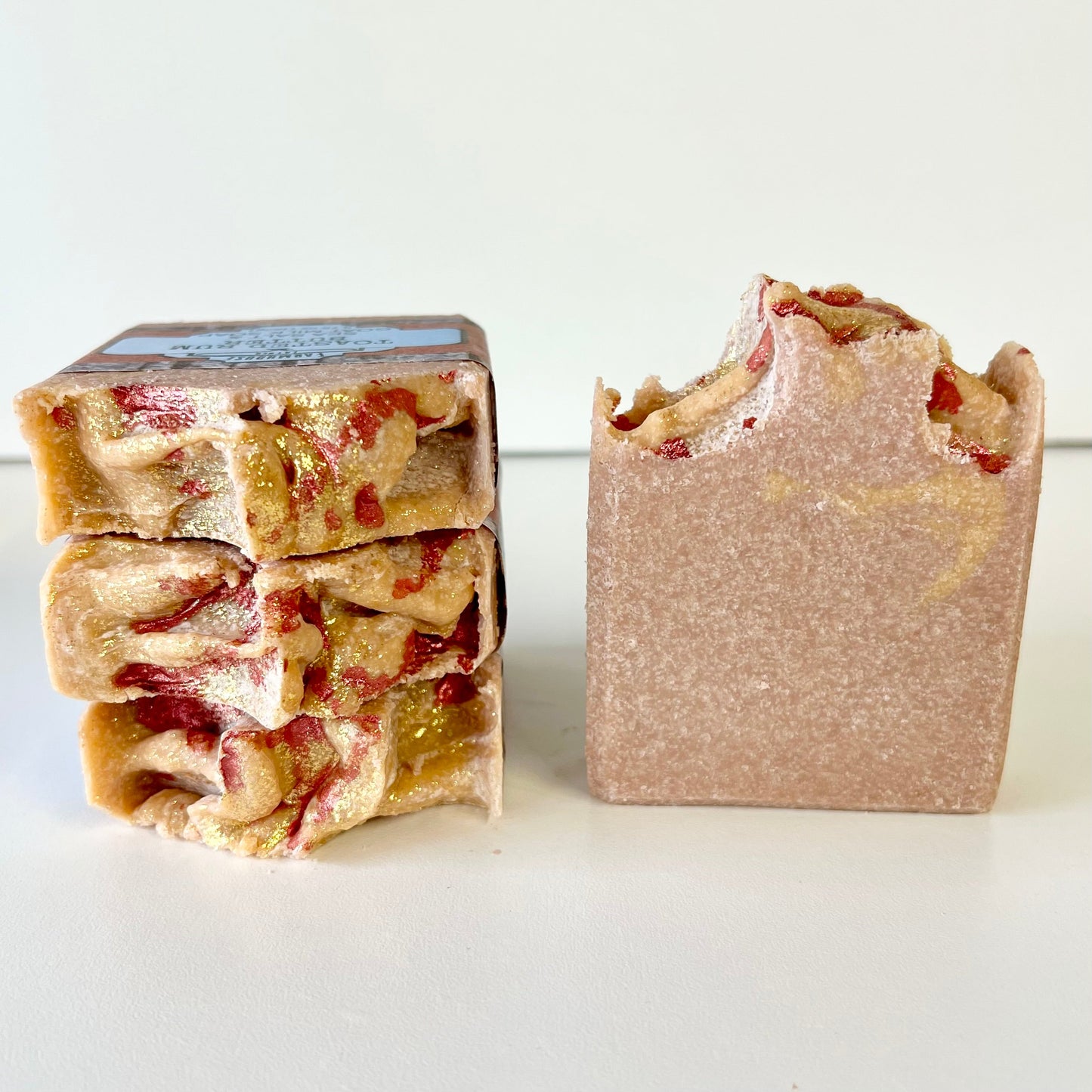 Goat milk soap bar with red streaks, wrapped paper bar and view