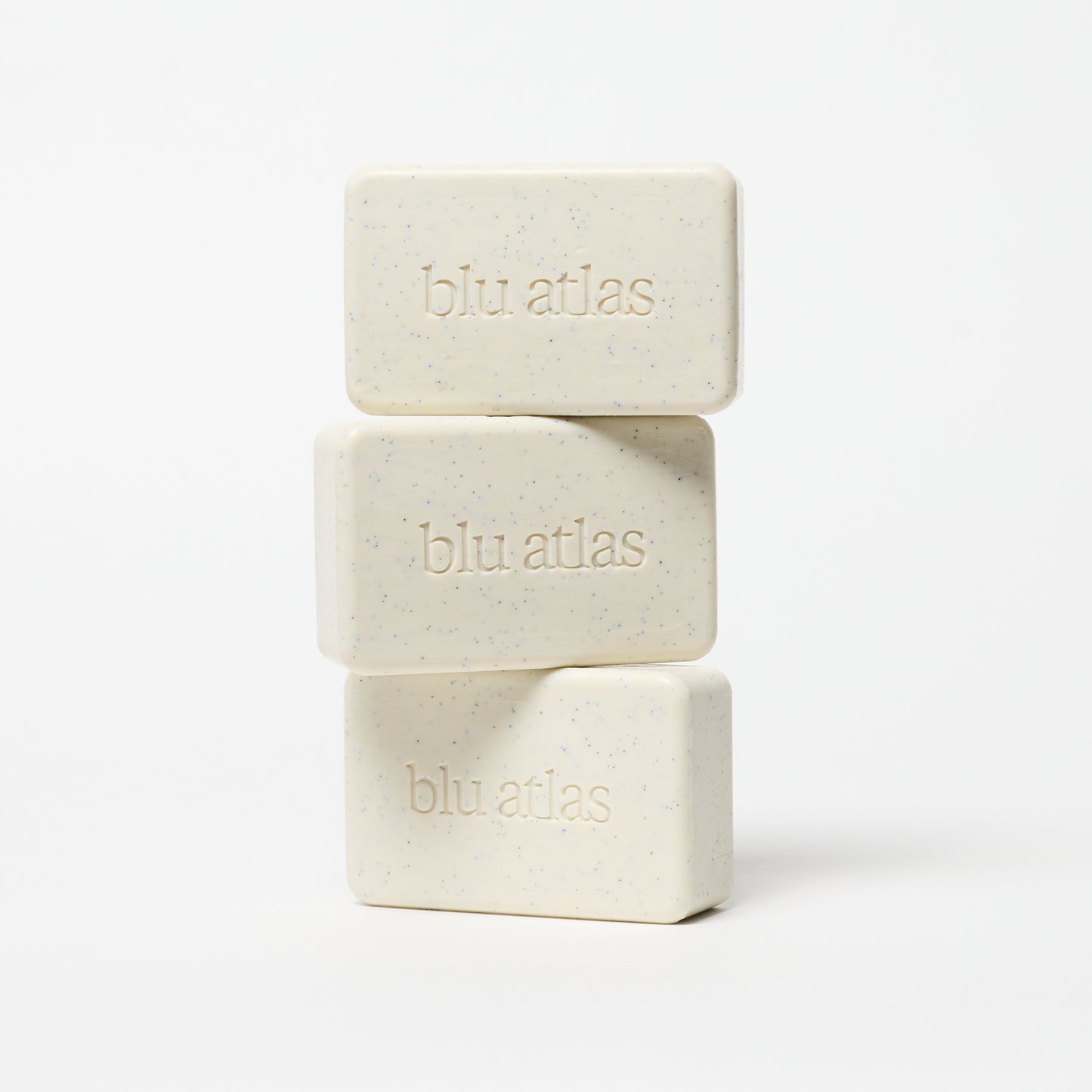 Stack of exfoliating bar soaps, pale cream with blue specks and blu atlas logos