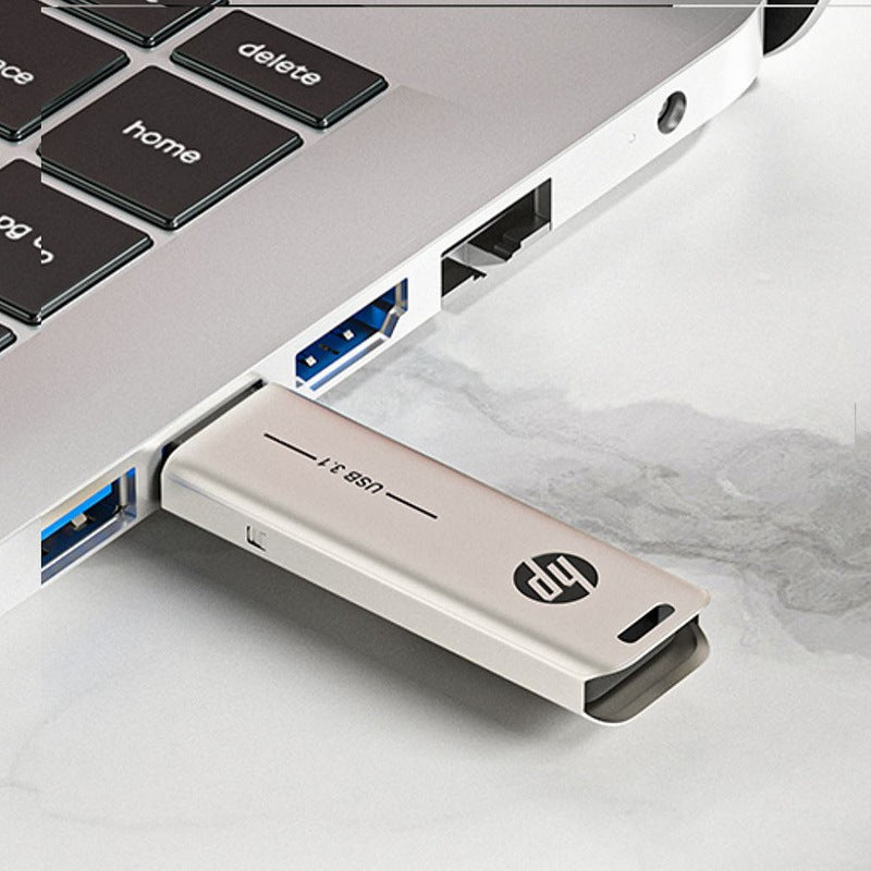 HP USB flash drive inserted into a USB port, metallic silver body with HP logo