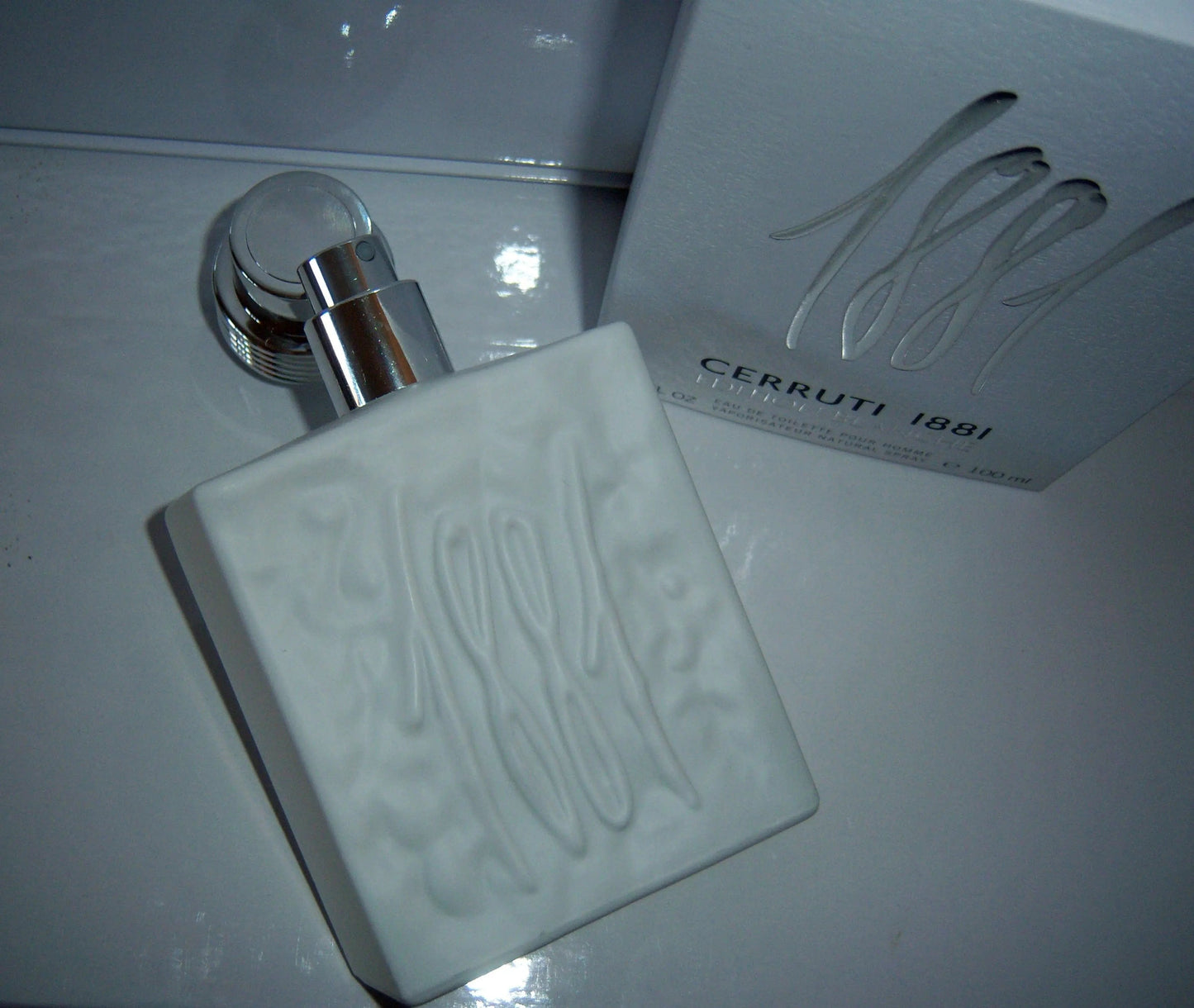 Clear eau de toilette bottle with chrome pump and matching box