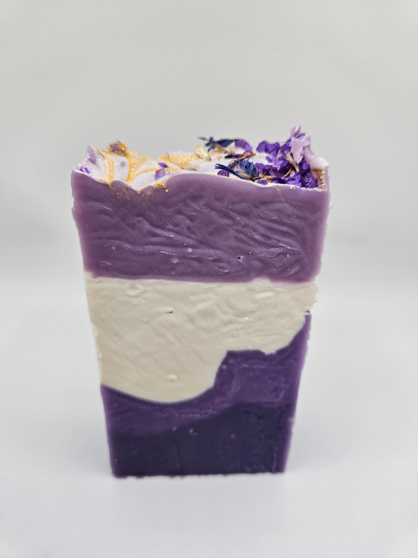 Lavender artisan soap bar with purple, cream layers and dried flower garnish on top