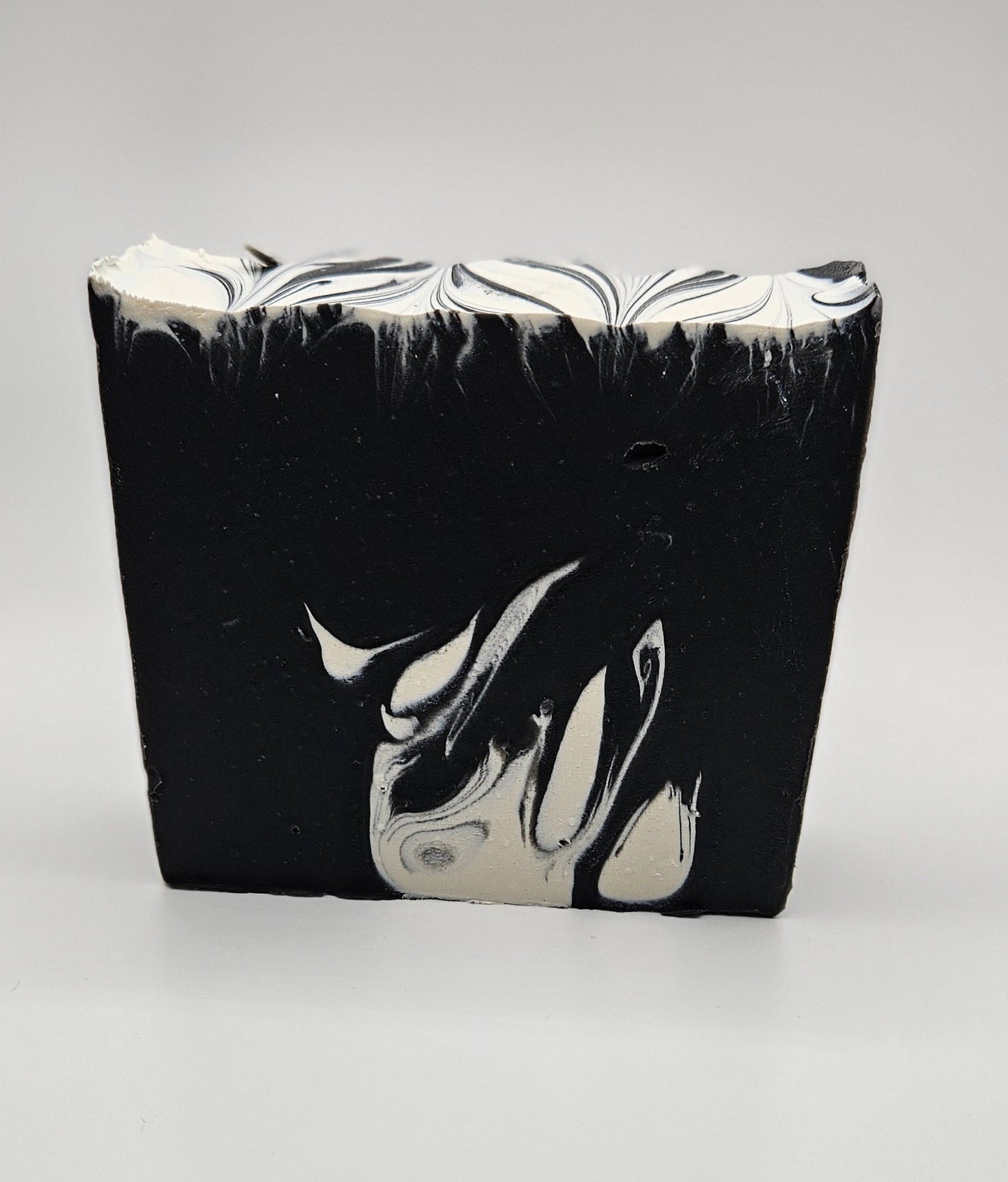Artisan soap bar, dark charcoal with white marbled swirls and wavy top