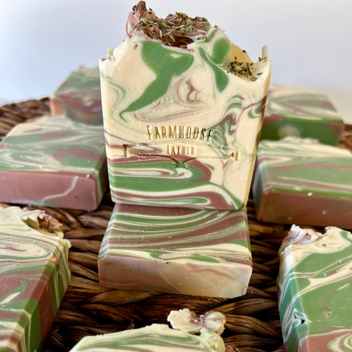 Marbled soap bar with green and cream swirls, with other bars behind