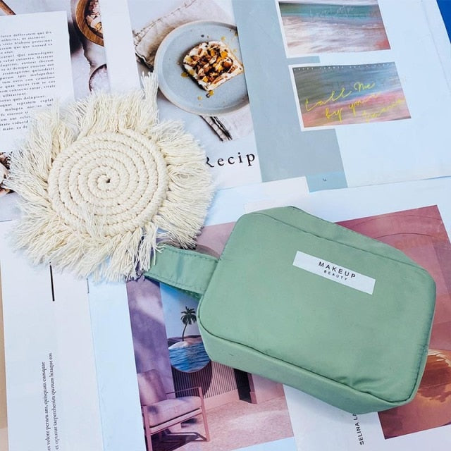 Cosmetic pouch green, zip-top with white front label and rounded rectangular shape.