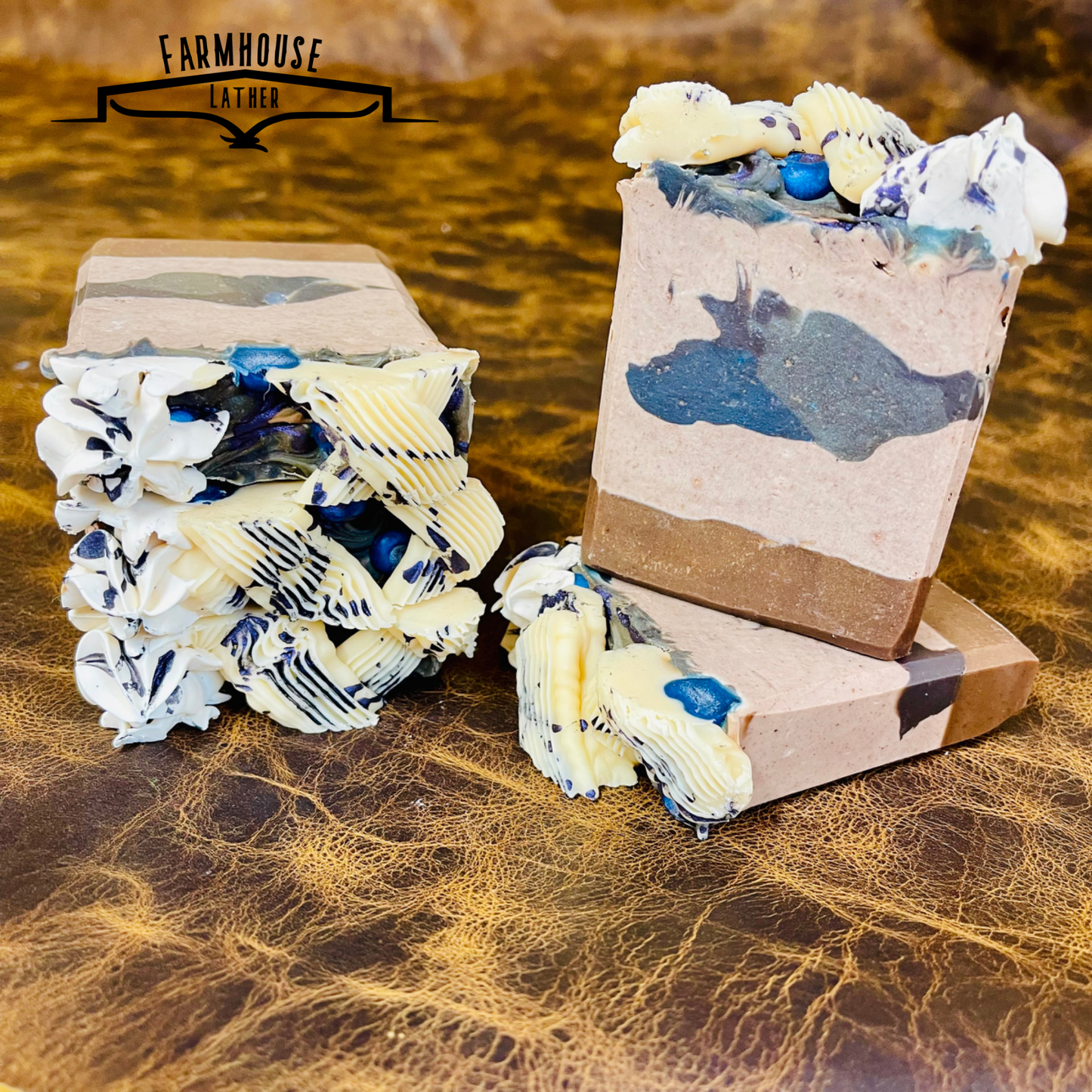Handmade soap bars with blue patches, white cream swirls, and layered ends