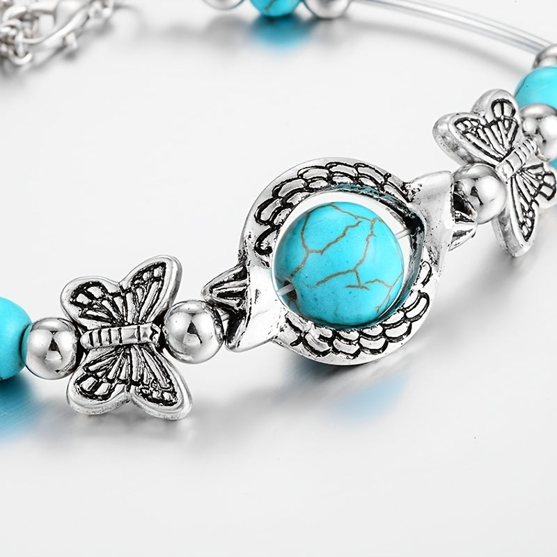 Silver-tone turquoise bracelet close-up: central cabochon with butterfly charms