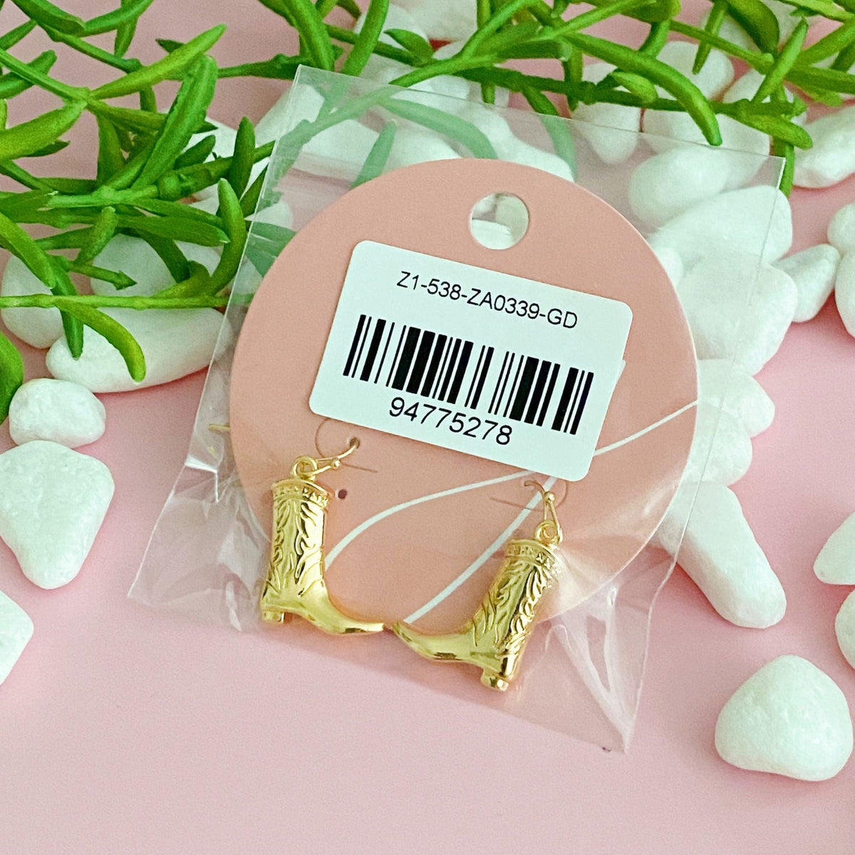 Gold-tone cowgirl boot dangle earrings on a retail tag backing