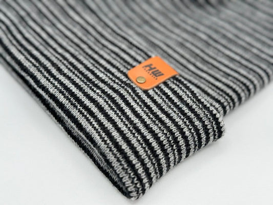 Cuffed black-and-gray striped beanie, close-up of cuff and brand label