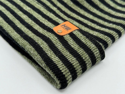 Striped knit beanie cuff close-up with orange logo patch on dark green base