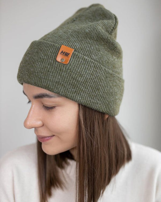Forest green knit beanie with fold-up cuff and small rectangular logo patch