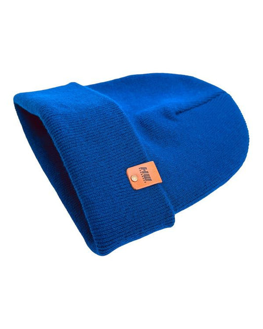 Cuffed knit beanie in sapphire blue, folded for a side view, with leather logo patch