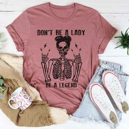 Rose-mauve graphic T-shirt with centered skull and “DON’T BE A LADY, BE A LEGEND”