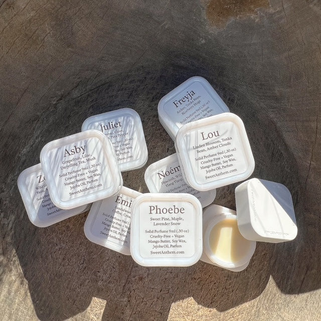 Assorted solid perfume jars, small square tins with white lids and printed labels