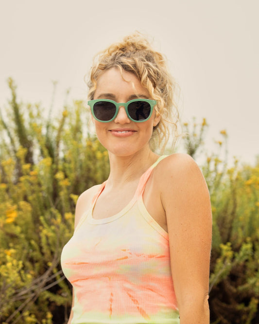 Green frame sunglasses with dark lenses on a woman, oval frames