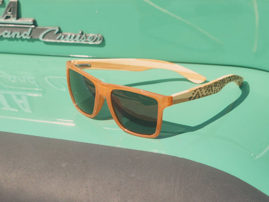 Polarized sunglasses with amber frame, patterned temples, and dark lenses