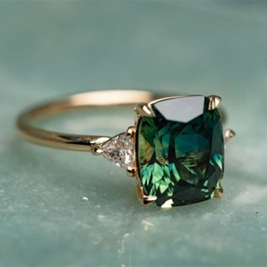 Gold ring with large green square-cut gemstone and two small clear side stones