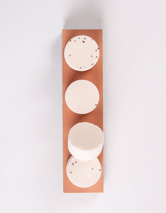 Shower steamer set of four pale round tablets with small speckles on brown sleeve