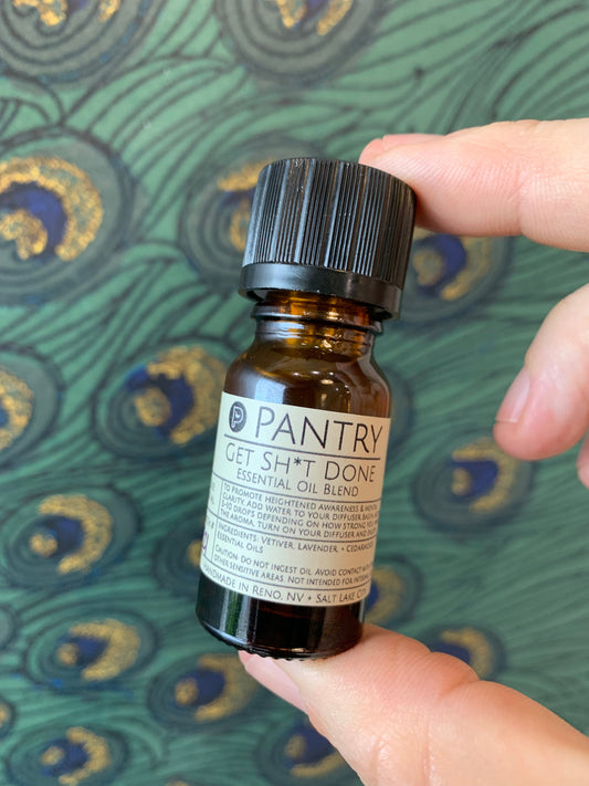 Essential oil blend bottle, dark glass with black cap; label shows Get Sh*t Done