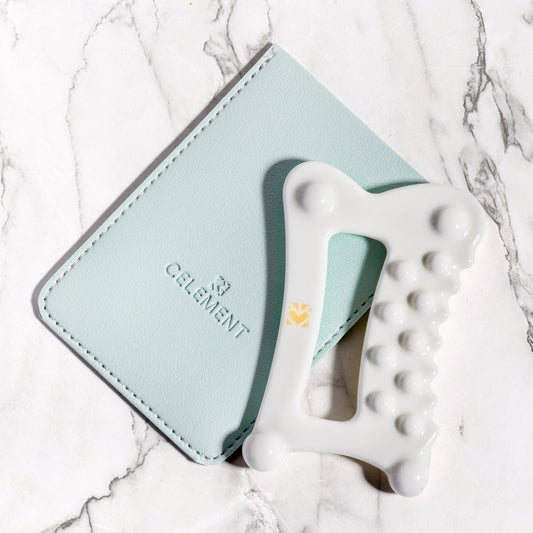 White ceramic gua sha face tool on mint case