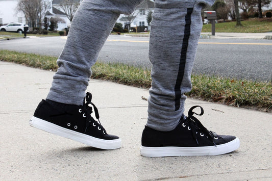 Black lace-up canvas sneakers with white soles on feet