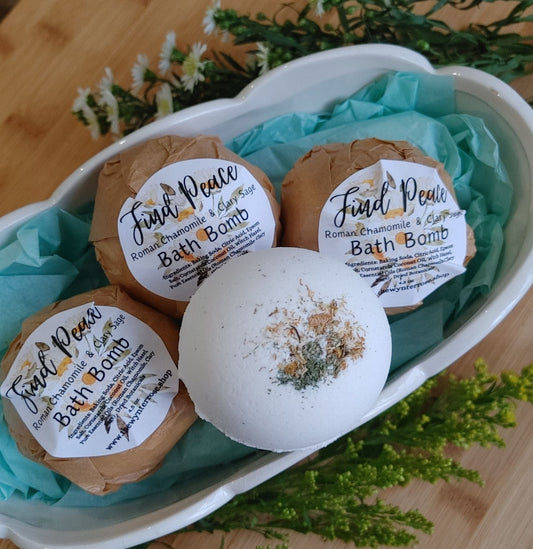 Three round bath bombs with printed labels in shallow tray, speckled surface