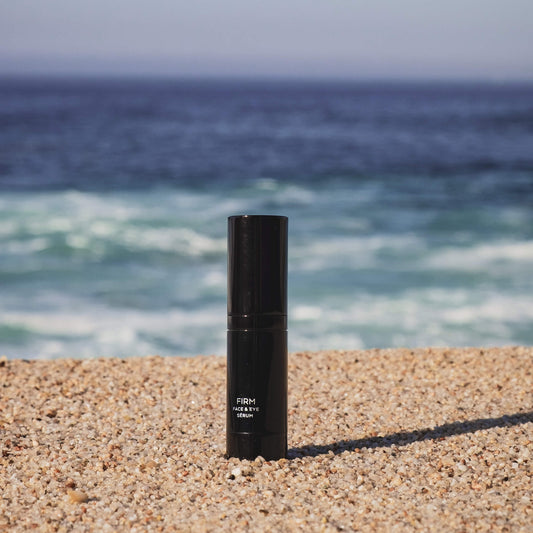 Firm serum bottle, black cylinder with flip-top pump and label on sand