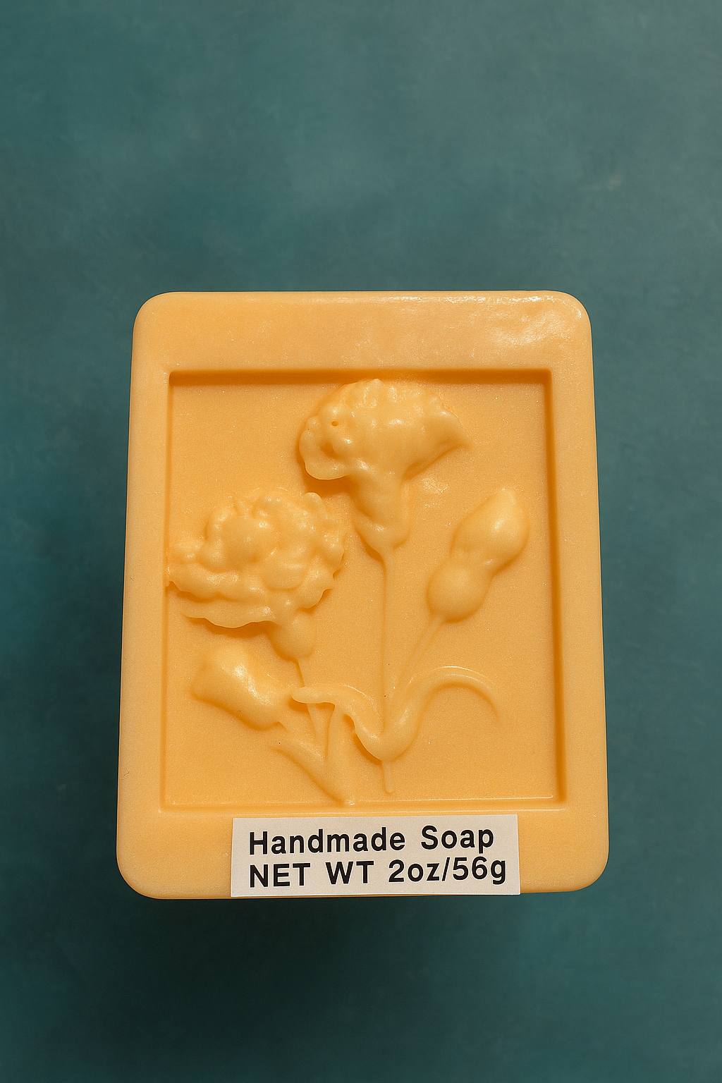 Orange handmade soap bar with raised floral embossing on a flat base