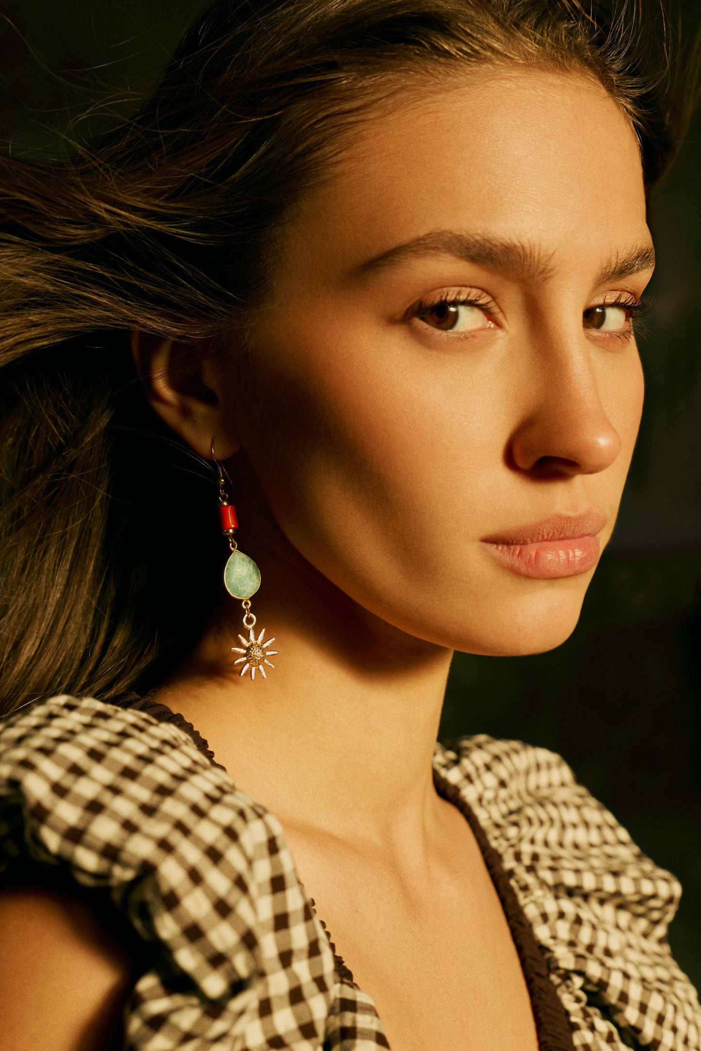 Gold-tone drop earrings on model: green teardrop stones, orange beads, sunburst charm.