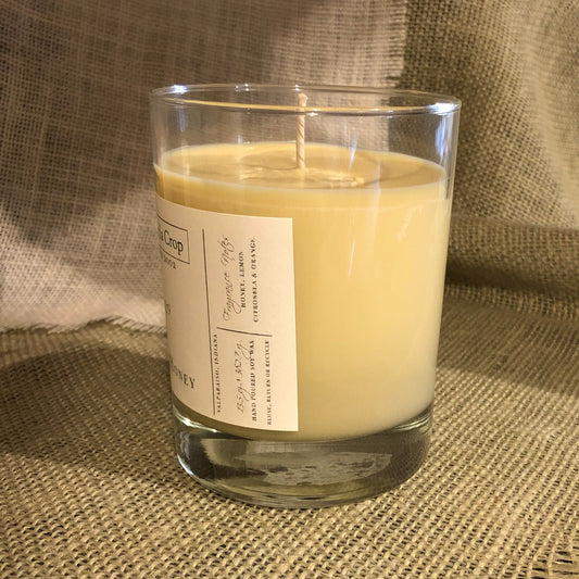 Soy candle in clear glass jar with label and yellow-gold wax