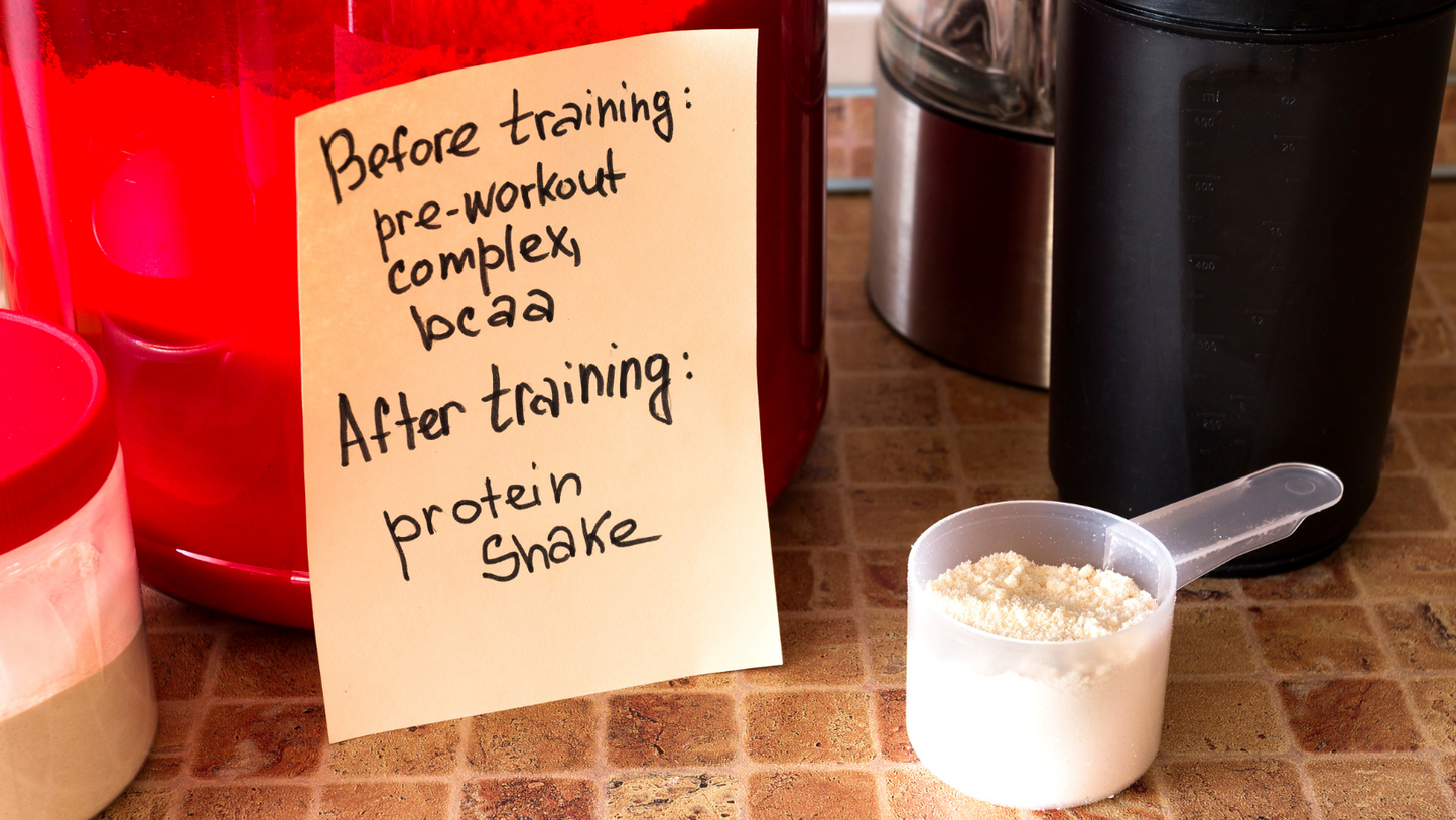 BCAA powder scoop with handwritten training note beside shaker bottles