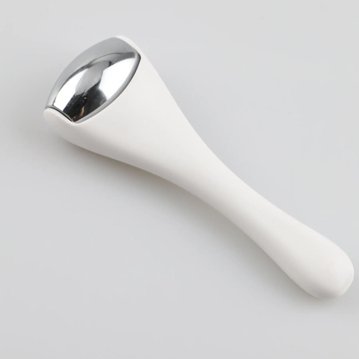 Ice roller massager on its side with white handle and silver roller head