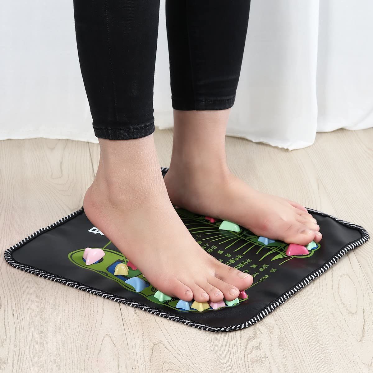 Foot pressure and massage mat under feet with colorful acupressure nodes