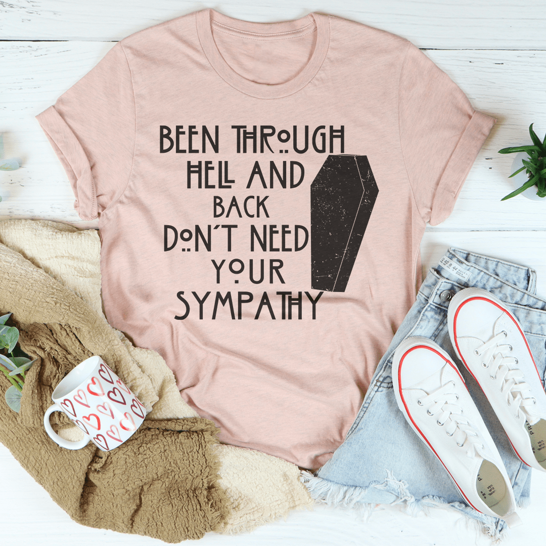 Blush pink graphic T-shirt with dark slogan text and tombstone-style print on front.