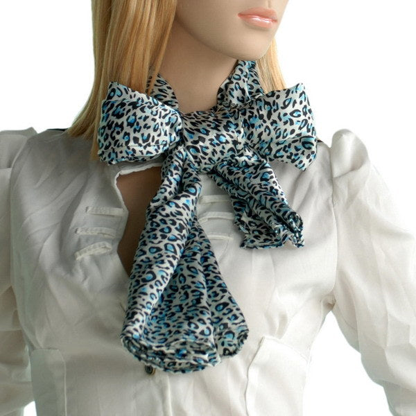 Leopard print silk scarf in teal and cream tied at neck with layered ends.