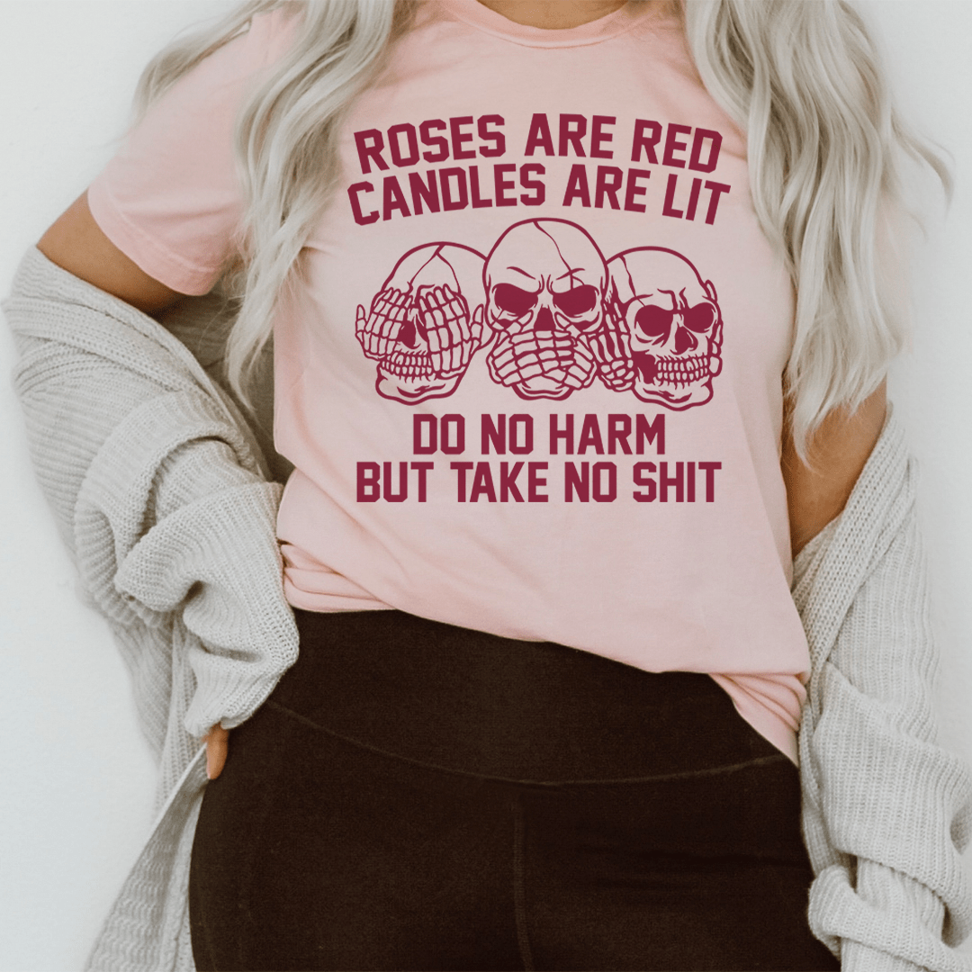 Pink crew-neck T-shirt with red skull/candle artwork and 'Do no harm' text