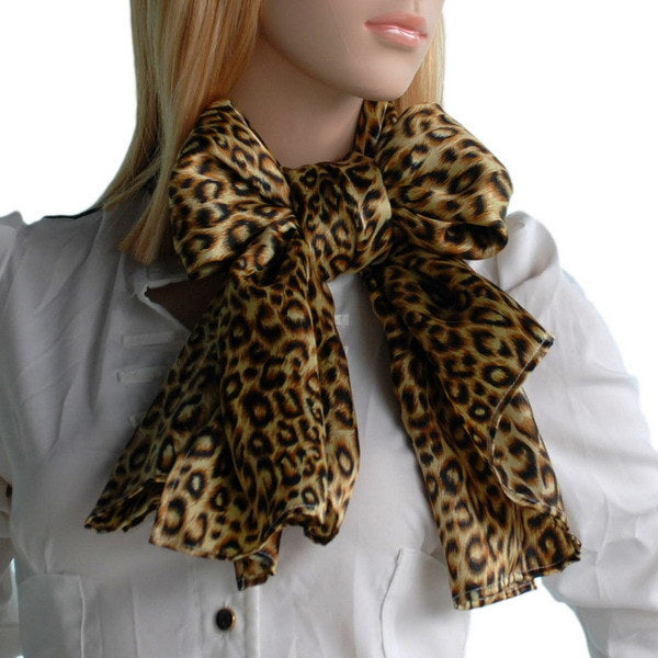 Leopard print silk scarf worn around neck with prominent knot in brown and black