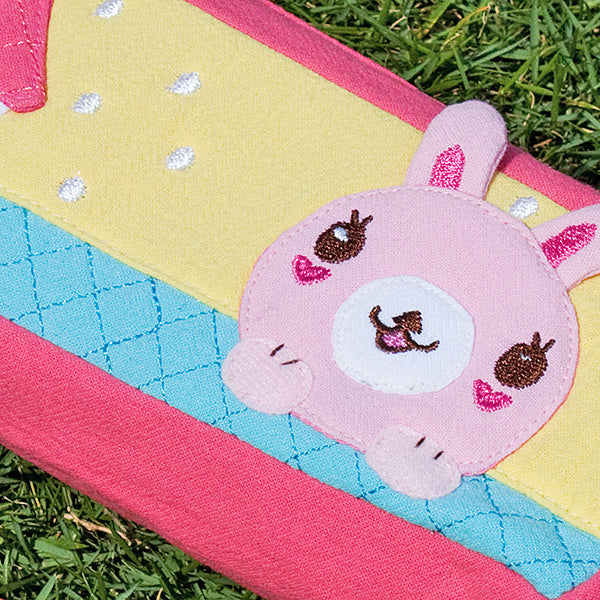Close-up embroidered rabbit face on pencil pouch, teal-blue quilted fabric with pink border