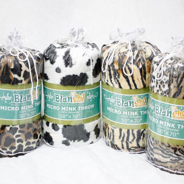 Animal print micro mink throw blankets in rolls, with green label bands