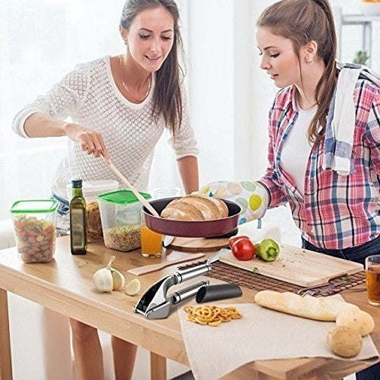 Garlic press in use on a kitchen table with two people preparing food.