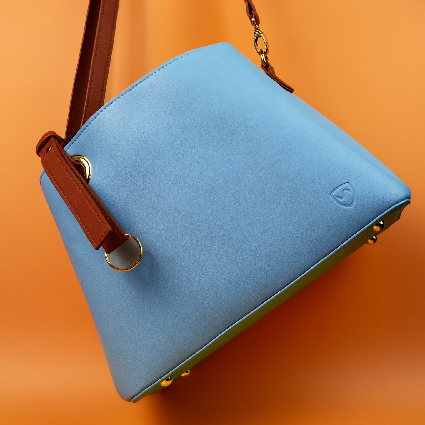 SYB blue shoulder purse with brown strap, embossed logo, and gold hardware