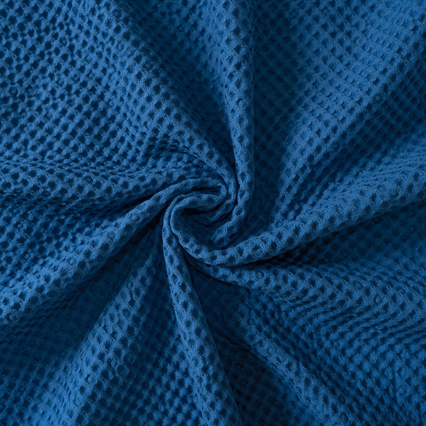 Blue waffle baby blanket with textured diamond knit, folded and bunched