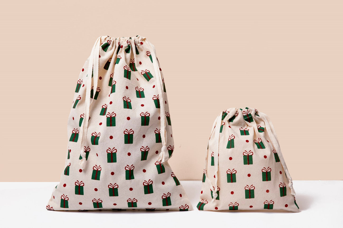 Two white cloth drawstring gift bags with gift icon print, gathered tops