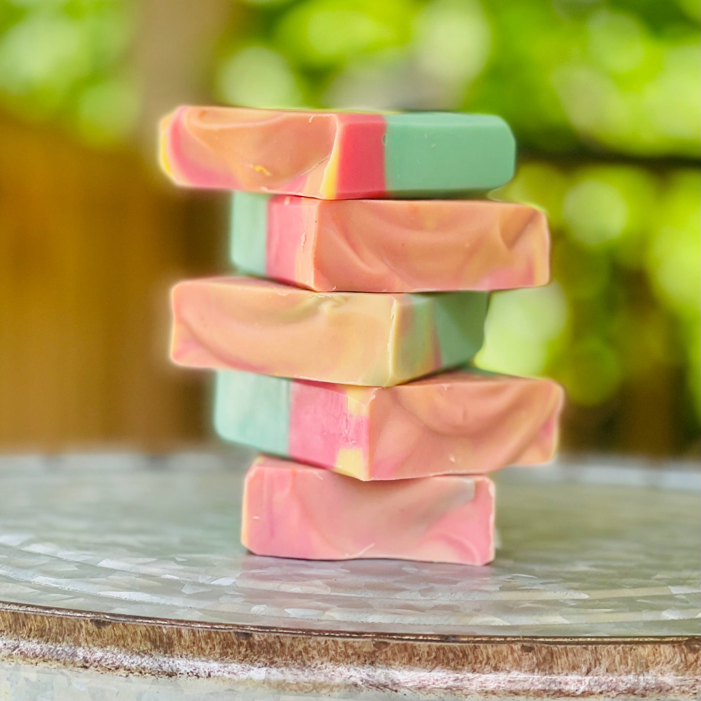 Stacked marbled soap bars in pink, teal, and orange on display.