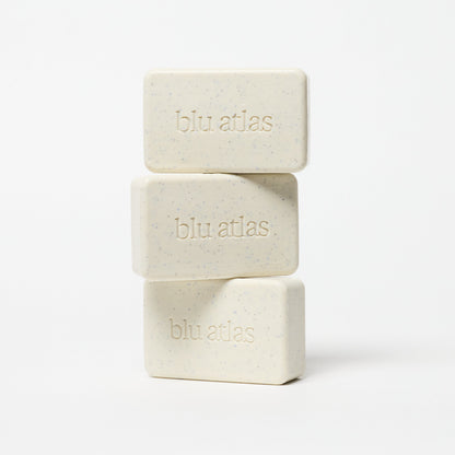 Stack of exfoliating bar soaps, pale cream with blue specks and blu atlas logos