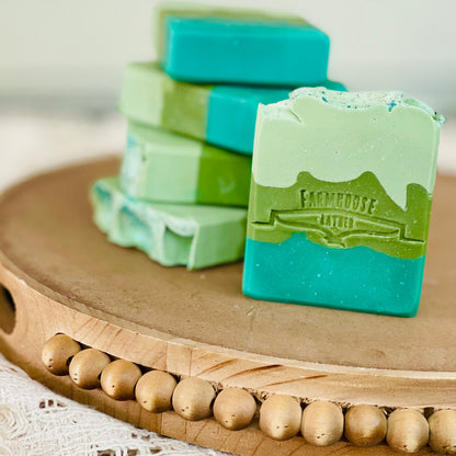 Teal and green soap bars with white tops, stamped logo detail
