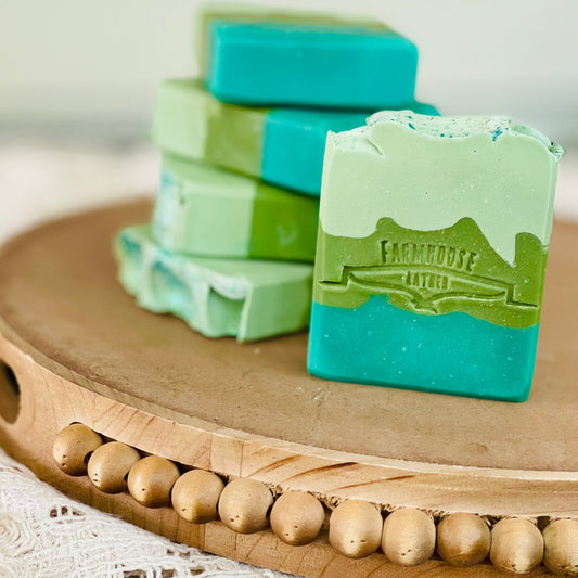 Teal and green soap bars with white tops, stamped logo detail