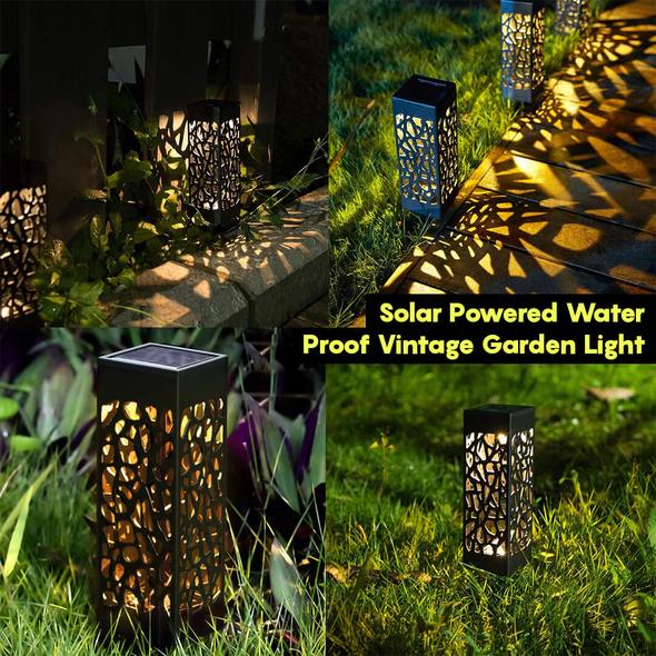 Black cutout solar garden light standing on lawn near walkway