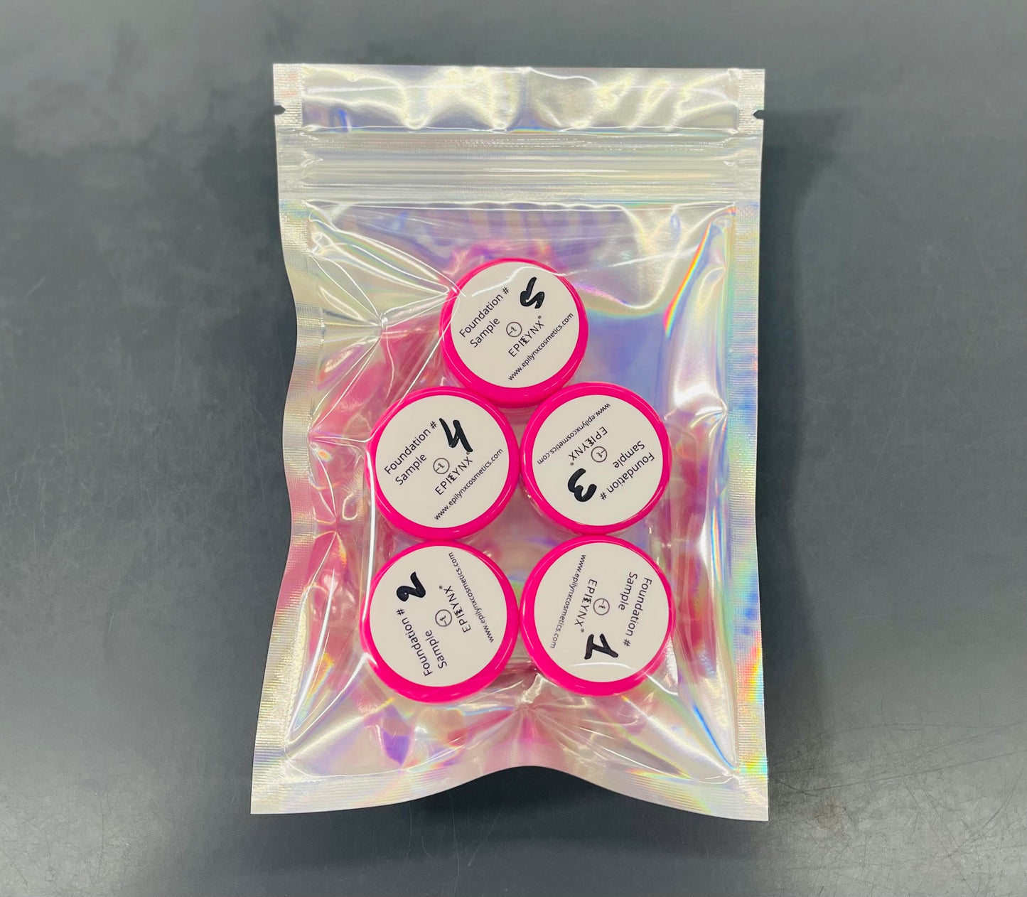 Foundation sample set with five circular lids in a pink holographic pouch.