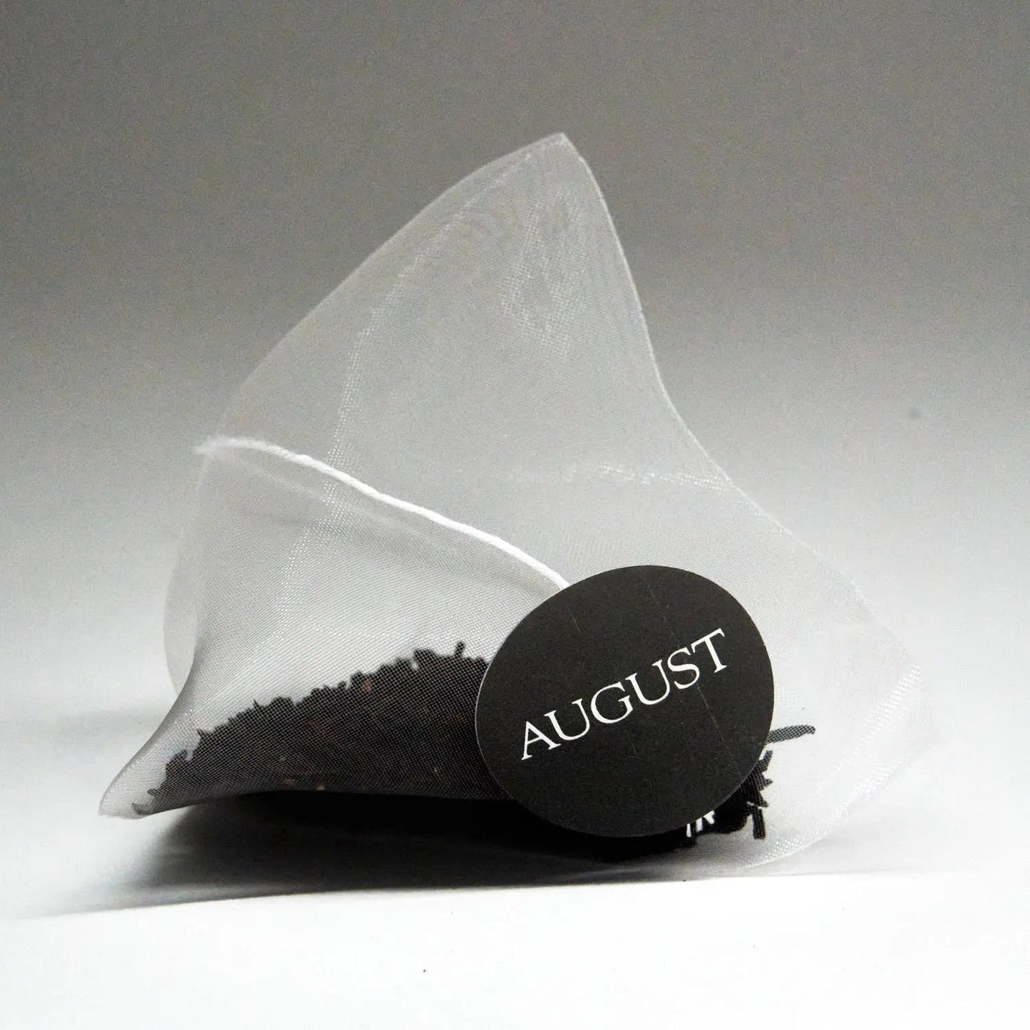 Pyramid tea bag sachet with round August brand seal