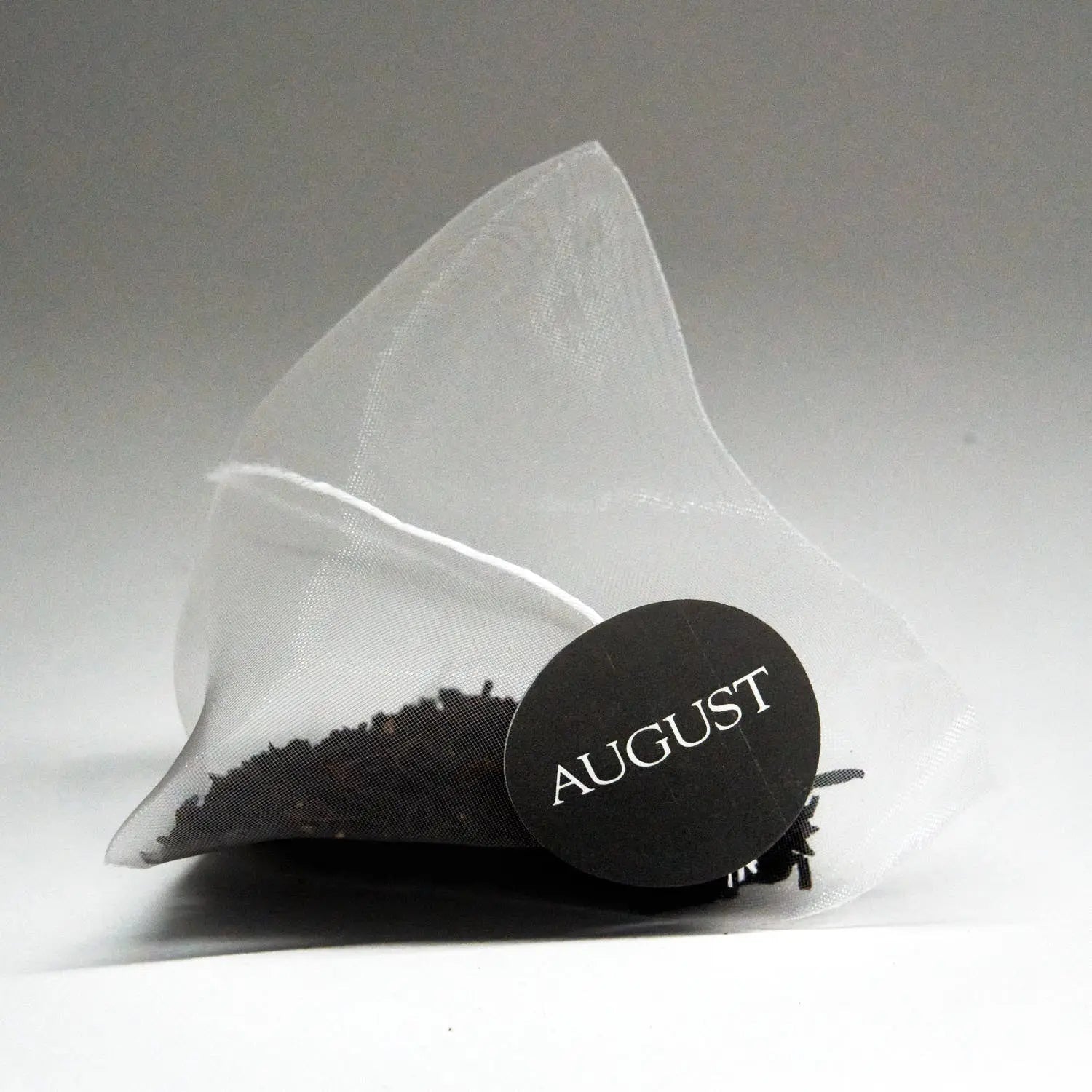 Pyramid tea bag sachet with round August brand seal